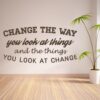 Primer izgleda čokoladne rjave stenske nalepke Change the way you look at things na beli steni. Nalepka je napis, ki se glasi: Change the way you look at things and the things you look at change.
