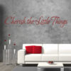 Primer izgleda rdeče samolepilne stenske nalepke Cherish the little things na sivi betonski steni v dnevni sobi. Nalepka je napis, ki se glasi: Cherish the little things.