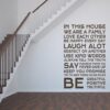 Primer izgleda čokoladno rjave samolepilne stenske nalepke House rules 3 na beli steni na hodniku. Nalepka je napis, ki se glasi: In this house: We are a family, Love each other, Be happy every day, LAUGH ALOT, Respect on another, Use kind words, Always tell the truth, Say okease and thank you, Never give up, Keep you promise, Try to keep these house rules, BE greatful, positive and truthful!