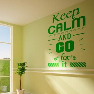 Primer izgleda zelene samolepilne stenske nalepke Keep calm and go for it na rumeno zeleni steni. Nalepka je napis, ki se glasi: Keep calm and go for it.