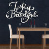 Primer izgleda bele samolepilne stenske nalepke Life is beautiful 2 na črni steni. Nalepka je napis, ki se glasi: Life is beautiful 2.