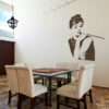 Primer izgleda čokoladno rjave samolepilne stenske nalepke Audrey Hepburn na bež steni v jedilnici.