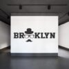 Primer izgleda črne samolepilne stenske nalepke Brooklyn Sir na beli steni v studiu. Na nalepki piše: Brooklyn