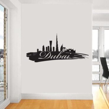 Primer izgleda črne samolepilne stenske nalepke Dubai packa na beli steni.