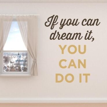 Primer izgleda rjave samolepilne stenske nalepke If you can dream it you can do it na bež steni v dnevni sobi.