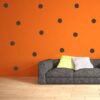 Primer izgleda črne samolepilne stenske nalepke Krogi 4 na oranžni steni v dnevni sobi.