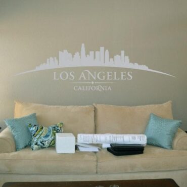Primer izgleda sive samolepilne stenske nalepke Los Angeles ukrivljen na bež steni nad sedežno v dnevni sobi. Na nalepki piše: Los Angeles, California