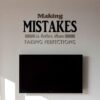 Primer izgleda črne samolepilne stenske nalepke Making mistakes is better then faking perfections na beli steni v dnevni sobi. Nalepka je napis, ki se glasi: Making mistakes is better then faking perfections.