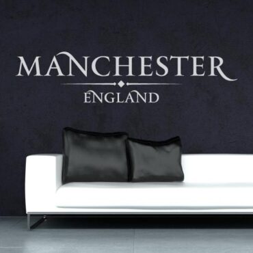 Primer izgleda bele samolepilne stenske nalepke Manchester England napis na črni steni v dnevni sobi.