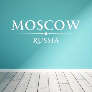 Primer izgleda bele samolepilne stenske nalepke Moscow Russia napis na turkizno zeleni steni v dnevni sobi.