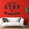 Primer izgleda črne samolepilne stenske nalepke Never stop dreaming na rdeči steni nad zofo v dnevni sobi. Nalepka je napis, ki se glasi: Never stop dreaming.
