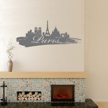 Primer izgleda grafitno sive samolepilne stenske nalepke Paris packa na bež steni v dnevni sobi.