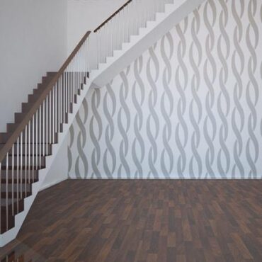 Primer izgleda sive samolepilne stenske nalepke Prepleten pas na beli steni na hodniku.