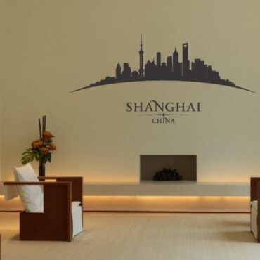 Primer izgleda črne samolepilne stenske nalepke Shanghai ukrivljen na beli steni v dnevni sobi.