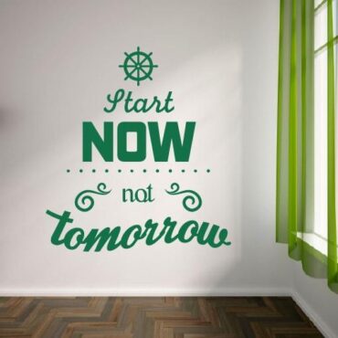 Primer izgleda zelene samolepilne stenske nalepke Start now not tomorrow na beli steni v dnevni sobi. Nalepka je napis, ki se glasi: Start now not tomorrow.