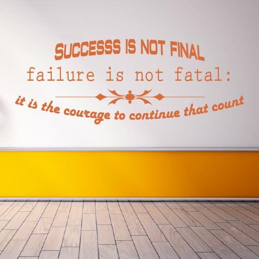 Primer izgleda oranžne samolepilne stenske nalepke Success is not final failure na beli steni v dnevni sobi. Nalepka je napis, ki se glasi: Success is not final failure is not fatal: it is the courage to continue that count.
