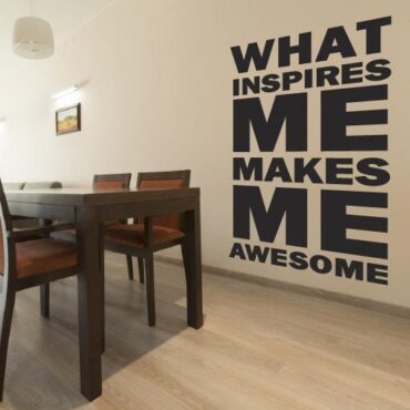 Primer izgleda črne samolepilne stenske nalepke What inspires me makes me awesome na bež steni v jedilnici. Nalepka je napis, ki se glasi: What inspires me makes me awesome.
