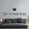 Primer izgleda črne samolepilne stenske nalepke You are simply the best na beli steni v spalnici. Nalepka je napis, ki se glasi: You are simply the best.