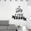 Primer izgleda črne samolepilne stenske nalepke You only live once na beli steni v dnevni sobi. Nalepka je napis, ki se glasi: You only live once.